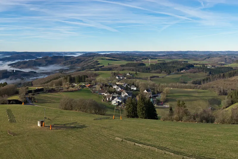 Η Wildewiese στους λόφους του Sauerland, με έναν αναβατήρα σκι στο λιβάδι και το χωριό από κάτω